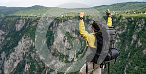 Hiker with backpacks reaches the summit of mountain peak. Success, freedom and happiness concept