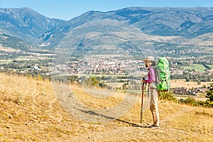 Hiker with big backpack stands on the rock and enjoys the valley view in Spanish Pyrenees mountains