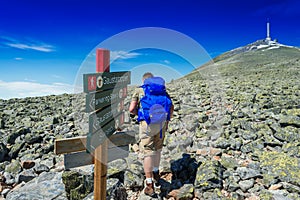 Hiker with big traveling rucksack looking forward on the mountai