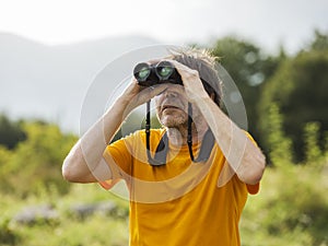 Hiker with binoculars observes birds in the mountains