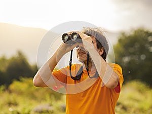 Hiker with binoculars observes birds in the mountains