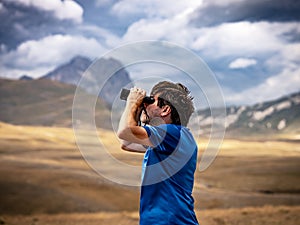 Hiker with binoculars observes birds in the mountains