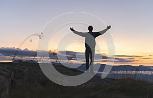 Hiker celebrating success on top of a mountain above the clouds. Young man enjoying freedome, Mountaineering sport lifestyle