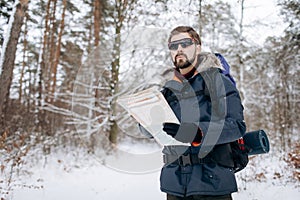 Hiker Checking Map to Orientate in Snow-clad Forest photo