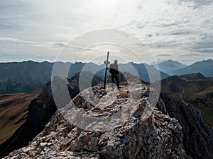 Hiker climber man on top of the rock wearing helmet looking at landscape. View from the back