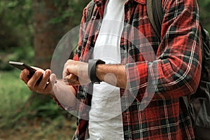 Hiker connecting smartwatch to smartphone to synchronize the data