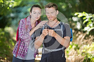 hiker couple looking at map and compass in forest
