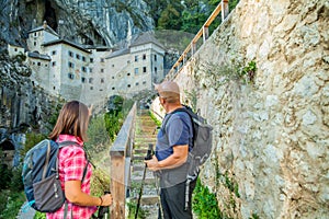 Hiker couple looking at the Predjama Castle in Slovenia