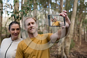 Hiker couple taking selfie with mobile phone in the forest