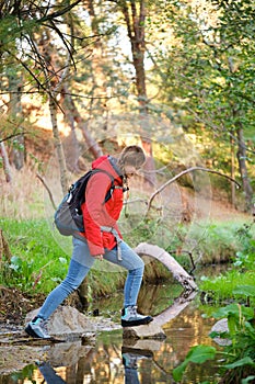 Hiker crossing a creek in a forest.