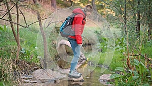 Hiker crossing a creek in a forest.