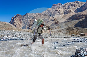 Hiker crossing mountain river