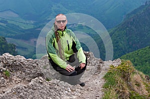 Hiker with dreadllocks on Maly Rozsutec, on background mountain village, Mala Fatra, Slovakia in spring cloudy morning