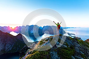 Hiker enjoying midnight sun during arctic summer, Reine, Lofoten, Norway