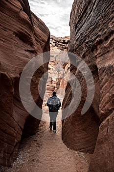 Hiker Exiting Narrow Slot Canyon On Cloudy Morning