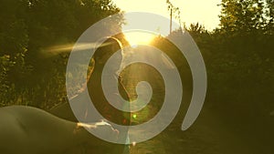 Hiker Girl with backpack holds man by hand and leads him. Young couple holding hands traveling on country road in rays