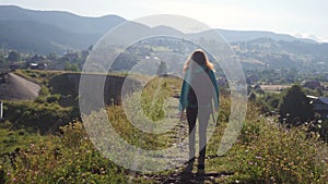 Hiker girl crossing the old stone bridge over the mountain river at the bright summer day