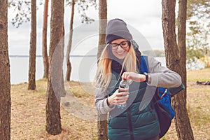 Hiker girl enjoying water. Happy woman tourist with backpack drinking water from bottle in nature.