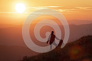 Hiker girl with heavy backpack looking at the sunset high in the mountains