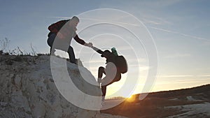 Hiker helping girlfriend while trekking on hill. Climber helping teammate climb, the man with the backpack reached out a