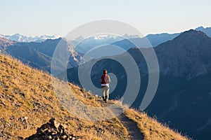 Hiker in high altitude rocky mountain landscape. Summer adventures on the Italian French Alps, toned image.