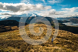 A hiker hiking on the beautiful track with a landscape of the mountains and Lake Wanaka. Roys Peak Track, South Island, New