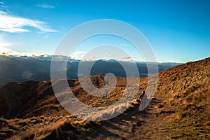 A hiker hiking on the beautiful track with a landscape of the mountains and Lake Wanaka. Roys Peak Track, South Island, New