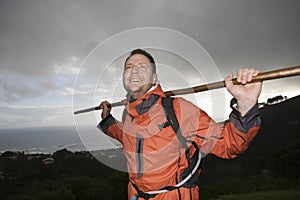 Hiker Holding Stick Across Shoulders On Hillside