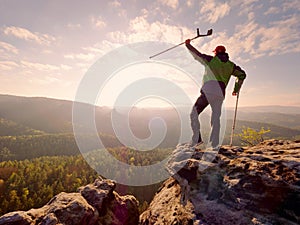 Hiker with hurts knee. Man with leg in join immobilizer stay on summit and raise medicine crutch