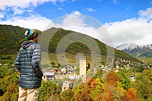 Hiker Impressed by the Panoramic View of Mestia Town with Svan Tower-houses Among the Fall Foliage, Svaneti Region of Georgia