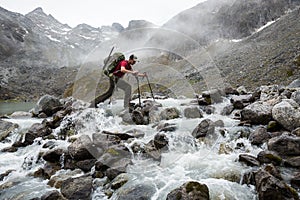 Hiker with large pack crossing a rocky river