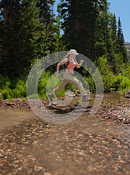 Hiker leaping over stream