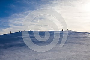 Hiker  with long shadow on top of Mount Ciucas peak on a sunny winter day at sunset