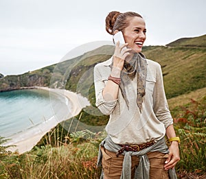 Hiker looking aside and using mobile phone in front of ocean