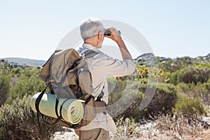 Hiker looking through binoculars on country trail
