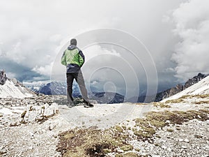 Hiker man with backpack crossing stream on stones in Dolomiti