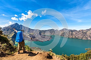 Hiker man with backpack spreading hand, enjoy and happy with active volcano Baru Jari, Lake Segara Anak and summit of Rinjani moun photo