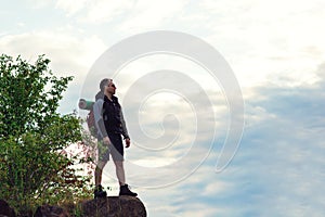 Hiker man with backpack standing on top of the mountain