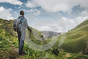 Hiker Man With Backpack And Trekking Poles Resting And Looking At The Mountains In Summer Outdoor, Rear View