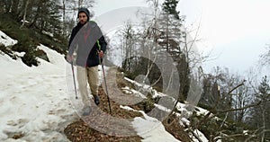 Hiker man with backpack walking on snowy trail path.Following front.Real backpacker people adult hiking or trekking in
