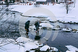 Hiker man crossing the river outdoor in winter