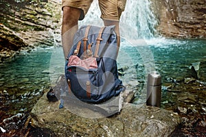 Hiker Man Feet, Backpack And Thermos On Waterfall Background Adventure Hiking Travel Concept