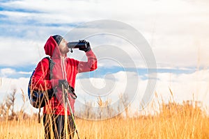 Hiker man in the field drinking water from water bottle