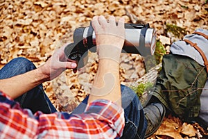 Hiker man pours tea from thermos photo