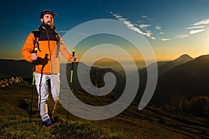 Hiker man practice nordic walking at sunset in the hills