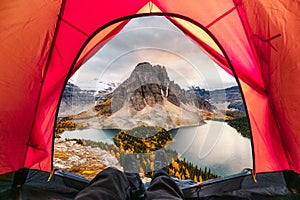 Hiker man relaxing in a tent with mount assiniboine view in autumn forest photo