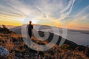 Hiker man with scenic sunrise view from top of mount Kula near Omis, Dinara mountains, Split-Dalmatia, Croatia. Coastal landscape
