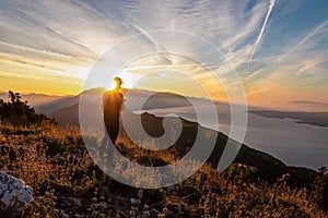 Hiker man with scenic sunrise view from top of mount Kula near Omis, Dinara mountains, Split-Dalmatia, Croatia. Coastal landscape