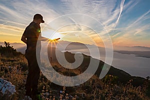 Hiker man with scenic sunrise view from top of mount Kula near Omis, Dinara mountains, Split-Dalmatia, Croatia. Coastal landscape