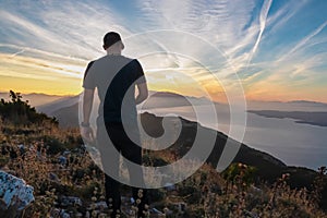 Hiker man with scenic sunrise view from top of mount Kula near Omis, Dinara mountains, Split-Dalmatia, Croatia. Coastal landscape